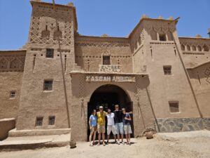 Travelers enjoying a Morocco vacation package with a camel trek across the Sahara Desert and stunning sunset views.